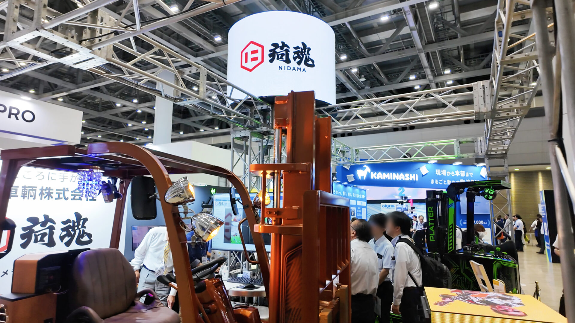 来場者でにぎわう日輸車輌ブースと円柱型LEDビジョン